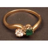 Mid-grade yellow metal emerald and diamond crossover ring, set with a square cut emerald and a