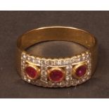 Three stone ruby and diamond ring, the three circular cut rubies set in a pierced mount surrounded