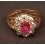 Mid-grade yellow metal ruby and diamond cluster ring, the centre oval cut ruby surrounded by eight