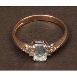 Modern 9ct gold blue topaz and diamond ring, the emerald cut centre topaz between small diamond