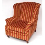 Victorian wing armchair upholstered in modern gold and burgundy striped designer fabric, raised on