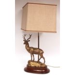 Decorative gilt metal table lamp, the base applied with figure of a stag standing on a rocky outcrop