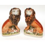 Pair of Staffordshire models of seated lions, each with a lamb at foot, painted in colours