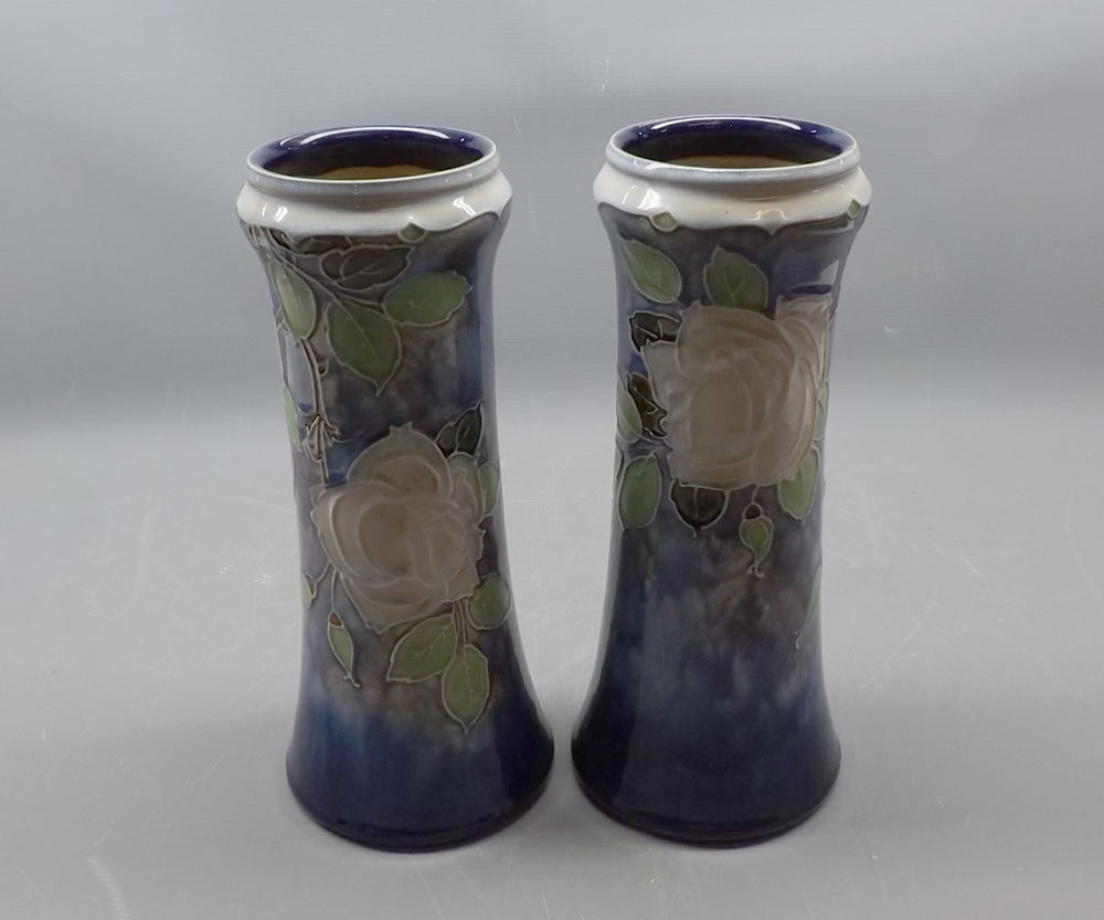 Pair of Royal Doulton stoneware cylindrical vases, decorated with stylised flowers on a blue