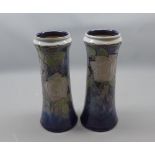Pair of Royal Doulton stoneware cylindrical vases, decorated with stylised flowers on a blue