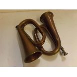 Two vintage copper horns, one marked "Rose-Morris, London" and the other marked "John Grey"