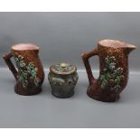 Graduated set of two Majolica ewers modelled as a tree trunk with floral raised relief, together