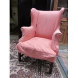 Georgian style winged arm chair covered in a coarse pink fabric