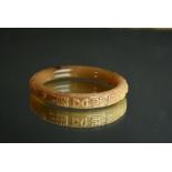 Chinese yellowish brown and russet jade bangle carved in low relief with chilong and four
