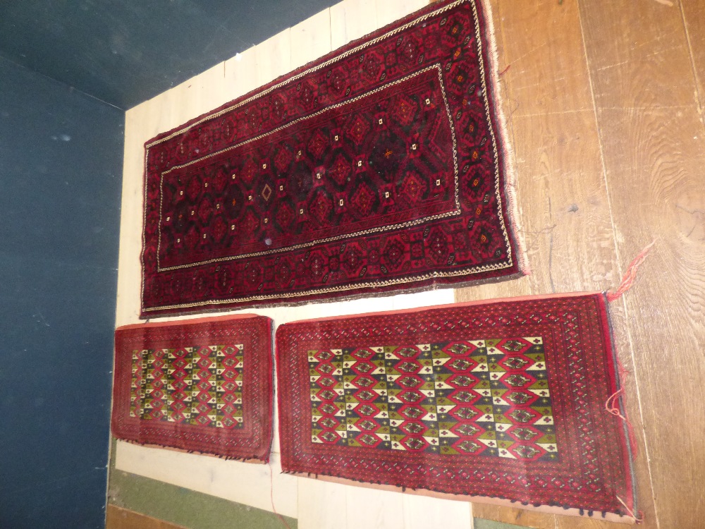 Modern Iranian rug patterned in black and white to a burgundy ground and two saddle bags