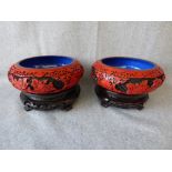 Pair of C20th Chinese cinnabar squat circular bowls on hardwood bases, overall height 11cm