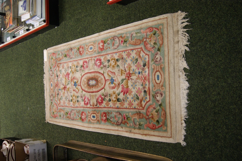 A thick-pile floor rug with geometric designs and flora against a cream ground.