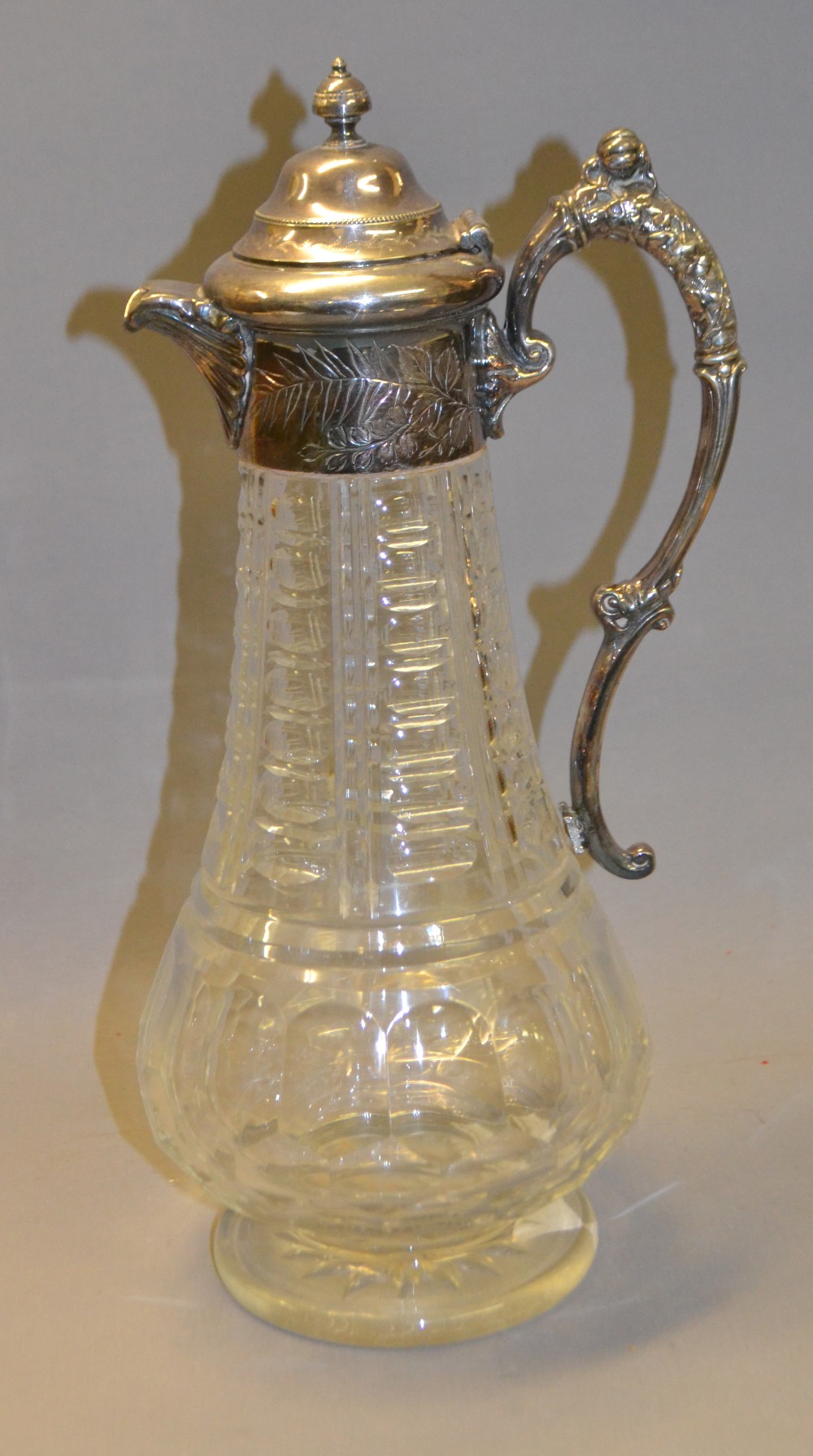 A good-quality cut-glass claret jug with a repoussé silver-plated mount