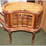 A French carved mahogany vitrine with glazed panels and of kidney form.