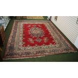 A traditional floor rug with floral decoration and geometric designs against a red and cream ground.