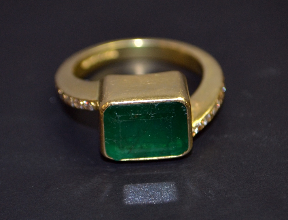 An 18ct yellow gold ladies dress ring with a large emerald and diamond shoulders. Marked .