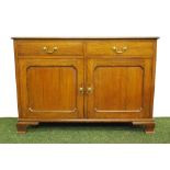 An Arts and Crafts oak sideboard of cupboards and drawers, raised on bracket feet.