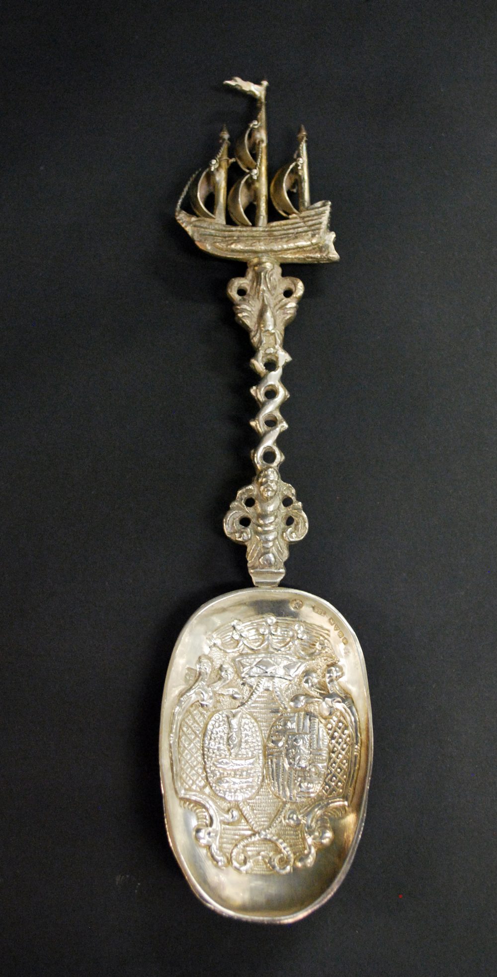 A hallmarked silver relief decorated spoon with the handle terminating in a galleon.