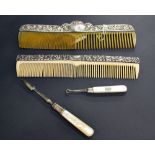 Two silver mounted combs together with a silver and mother of pearl button hook and a cuticle tool.