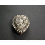 A hallmarked-silver repoussé decorated heart-shaped pill box having a gilt-washed interior.