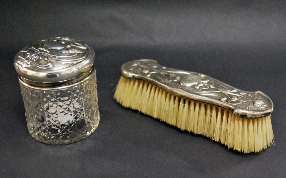 An Art Nouveau silver backed dressing brush along with a silver topped cut glass jar.