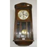An oak-cased wall clock with glazed single door,