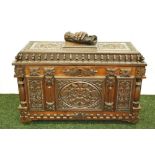 A heavily-carved oak chest the hinged cover bearing a carved hand clutching a scroll