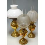 An early 20th century brass pedestal oil lamp having melon shaped clear glass globular shade