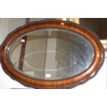 A faux walnut framed and bevelled oval wall mirror