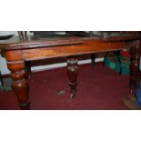 A Victorian mahogany round cornered extending dining table having pull-out action and on turned and