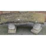 A contemporary reconstituted stone curved garden two-seater bench