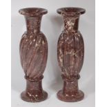 A near-pair of 19th century variegated rouge marble pedestal urns,