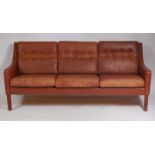 A 1960s Danish tan leather three seater sofa, raised on teak square cut supports, w.