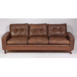 A 1960s Danish chocolate brown leather three seater sofa, raised on turned teak supports, w.