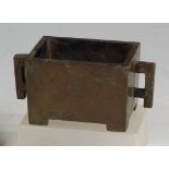 A Chinese bronze rectangular censor, having twin square handles and raised on low feet,