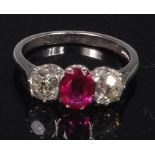 A platinum, ruby and diamond dress ring, arranged as an oval cut ruby weighing approx 0.