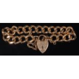 A heavy 9ct gold curblink bracelet with heart shaped padlock clasp and safety chain,