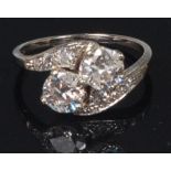 A white metal and diamond crossover ring, the two four claw set brilliants each weighing approx 0.