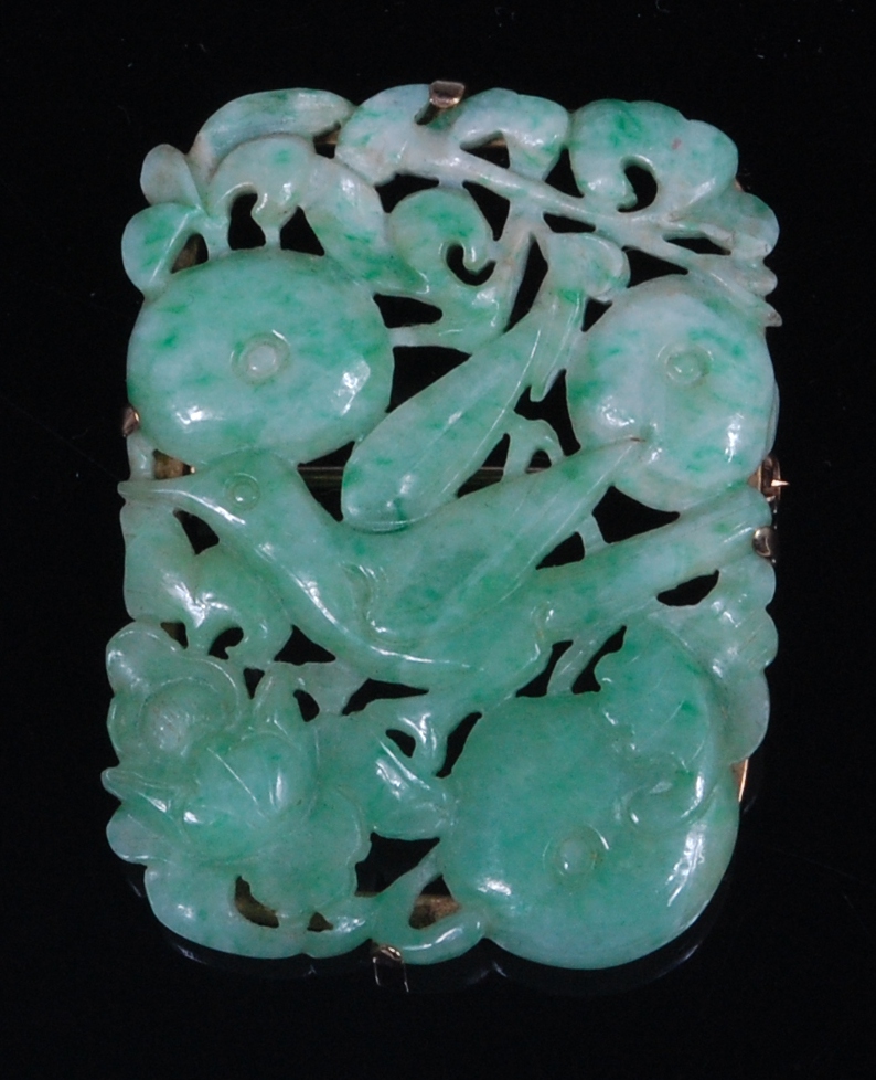 A Chinese celadon and green jade brooch, in yellow metal mount, carved as a bird amidst fruit,