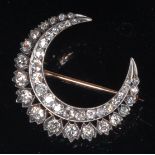 A circa 1900 yellow metal and diamond set crescent brooch,