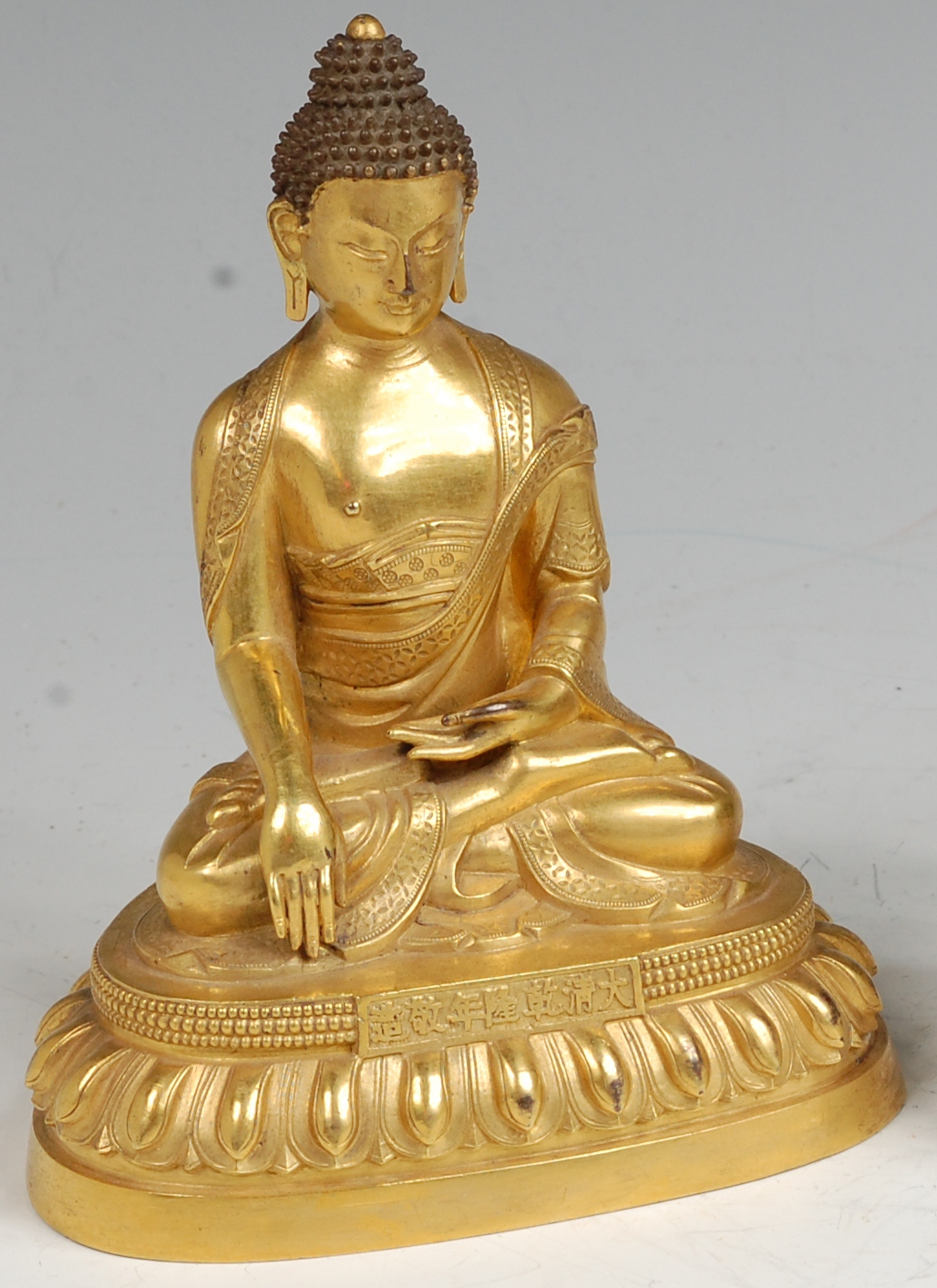 A Chinese finely cast gilt bronze Buddha, having a Qianlong seven character mark panel to the front,