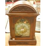 An early 20th century Continental walnut cased bracket clock having a brass arched dial with matt