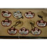 A cased set of seven enamelled decanter collars to include Port & Whisky, Cherry Whisky,