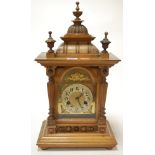 A late 19th century Continental walnut cased mantel clock having brass arched dial with silvered