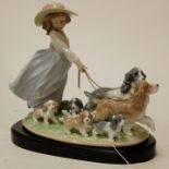 A large Lladro figure group modelled as a girl walking two dogs with various puppies