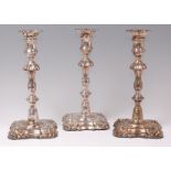 A set of three George IV chased silver table candlesticks, each with detachable sconces,