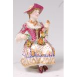 A 19th century English porcelain figure of a seated maiden, holding a garland of flowers,