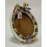 An early 20th century continental porcelain floral encrusted easel photograph frame surmounted by