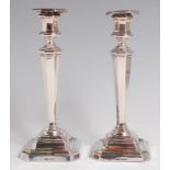 A pair of George V silver candlesticks, of tapering octagonal form, on stepped and loaded bases,