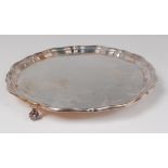 A silver salver, in the Georgian style, having a raised piecrust rim and on scroll feet, 17.